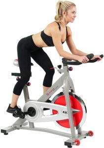 A lady riding the Sunny Health and Fitness Pro B901 Indoor Cycling Bike while standing