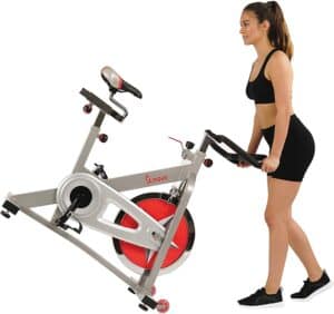 The Sunny Health and Fitness Pro B901 Indoor Cycling Bike is being moved for storage by a lady