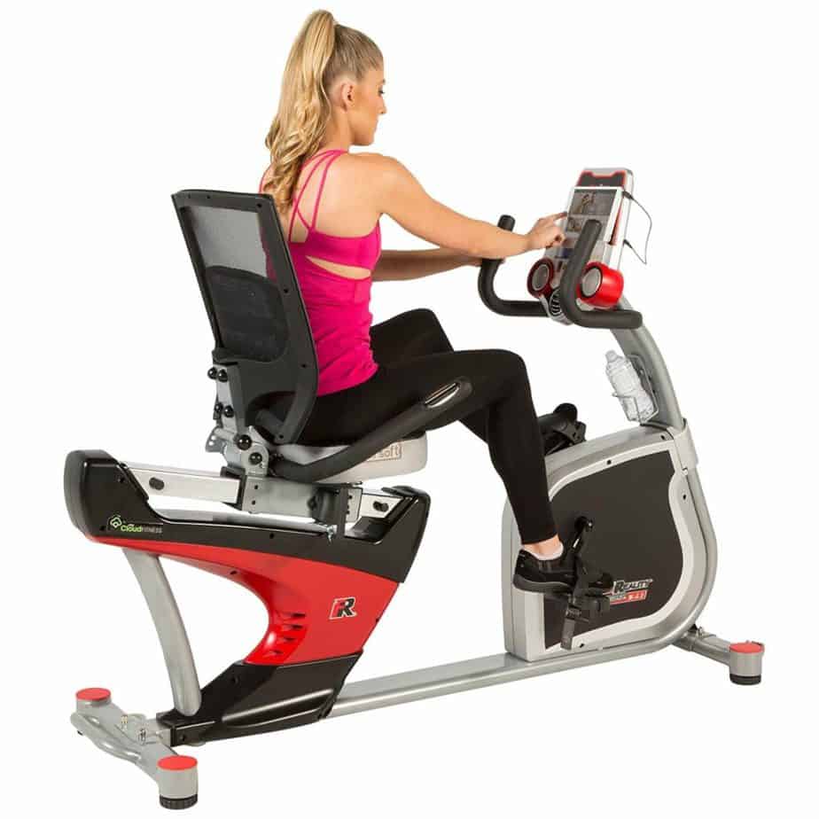 Fitness Reality X-Class 410 Recumbent Exercise Bike is being ridden by a woman