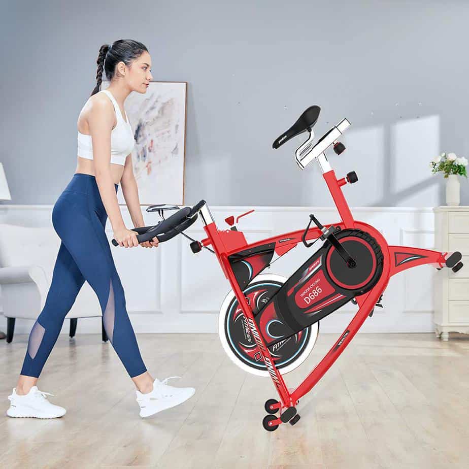 A lady rolls the Pooboo D686 Indoor Cycling Bike away to storage