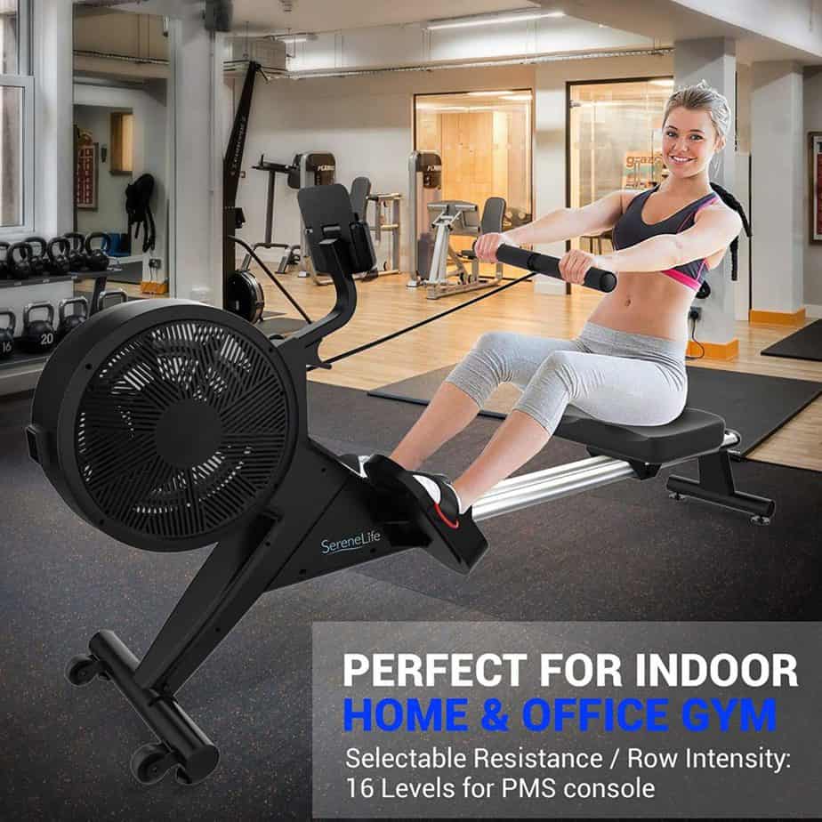 A lady is rowing with the SereneLife SLRWMC60 Smart Rowing Machine at home gym