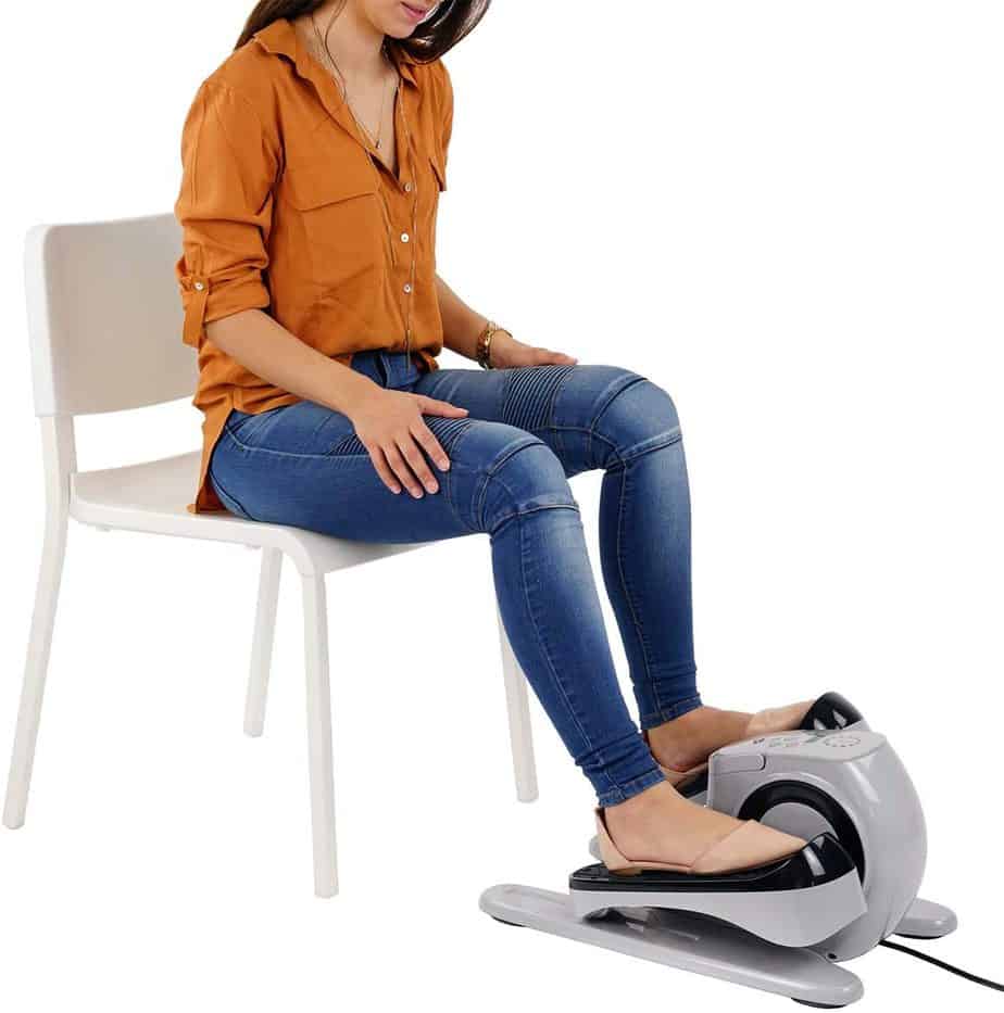 A lady is using the Sunny Health & Fitness SF-E3626 EZ Stride Motorized Elliptical while seated on a chair
