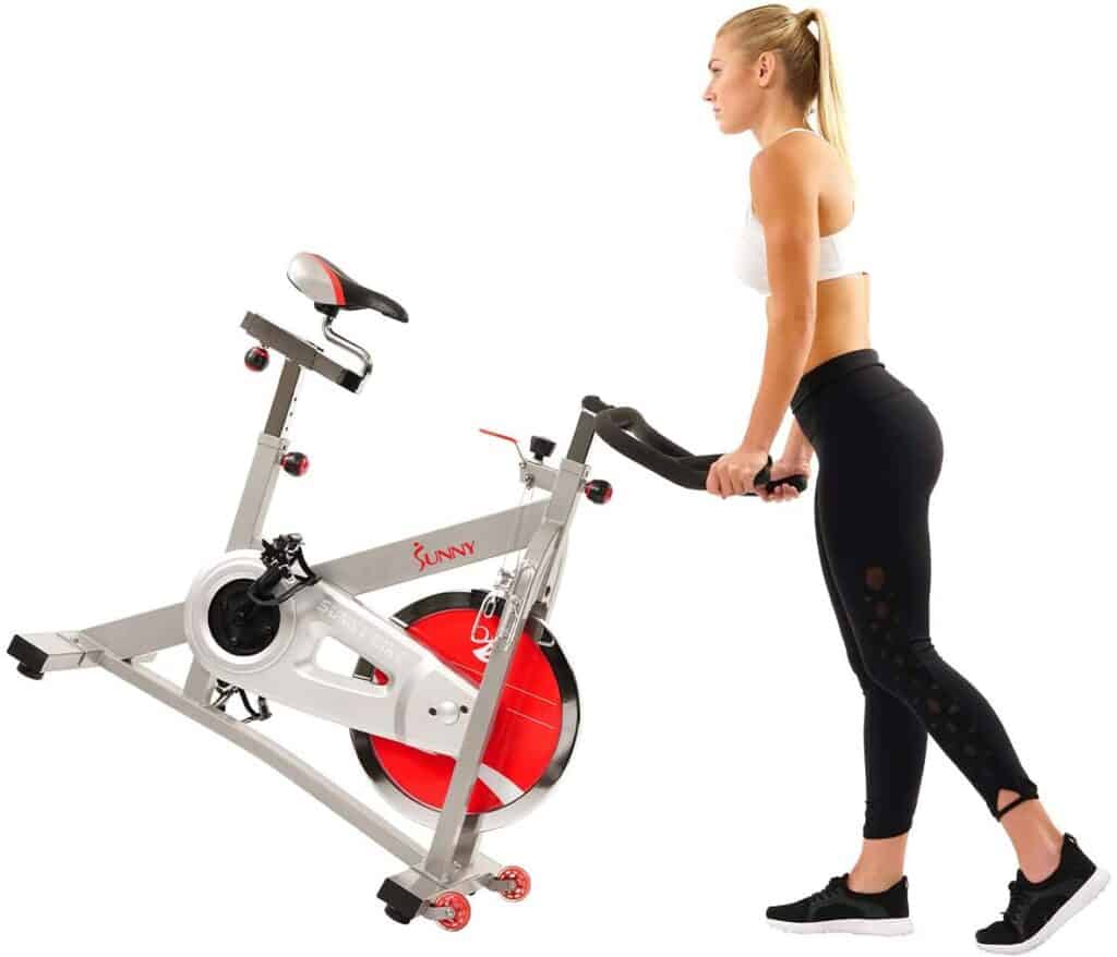 The user rolls away the Sunny Health and Fitness Pro SF-B901B Indoor Cycling Bike for storage