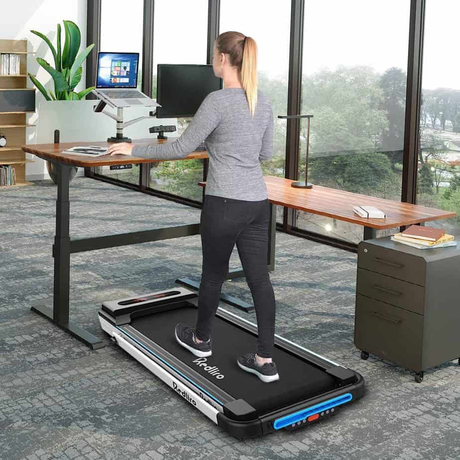 A lady walks on the Redliro Under Desk 2-in-1 Treadmill while working on the computer