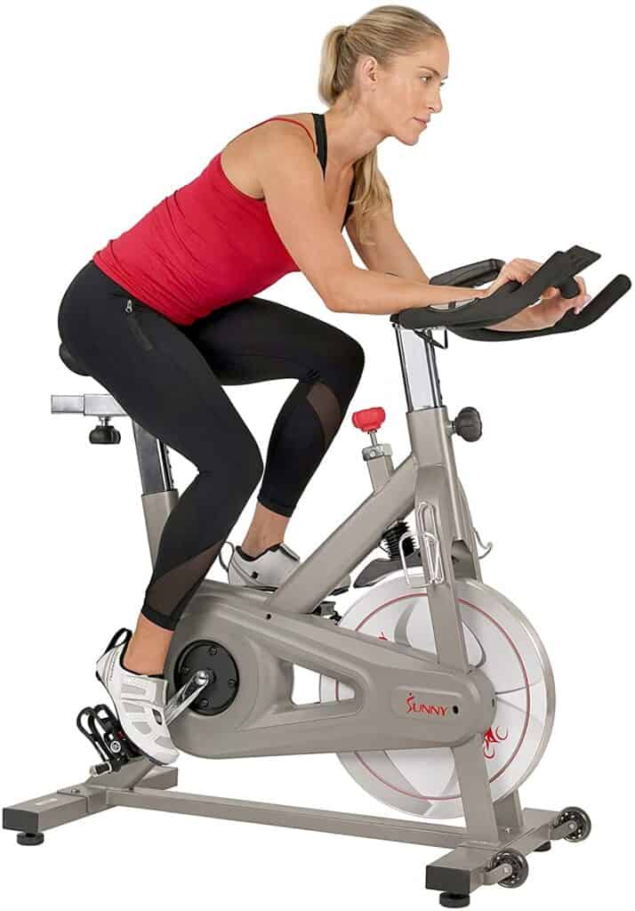 A lady exercises with the Sunny Health & Fitness SF-B1851 Synergy Pro Indoor Cycling Bike