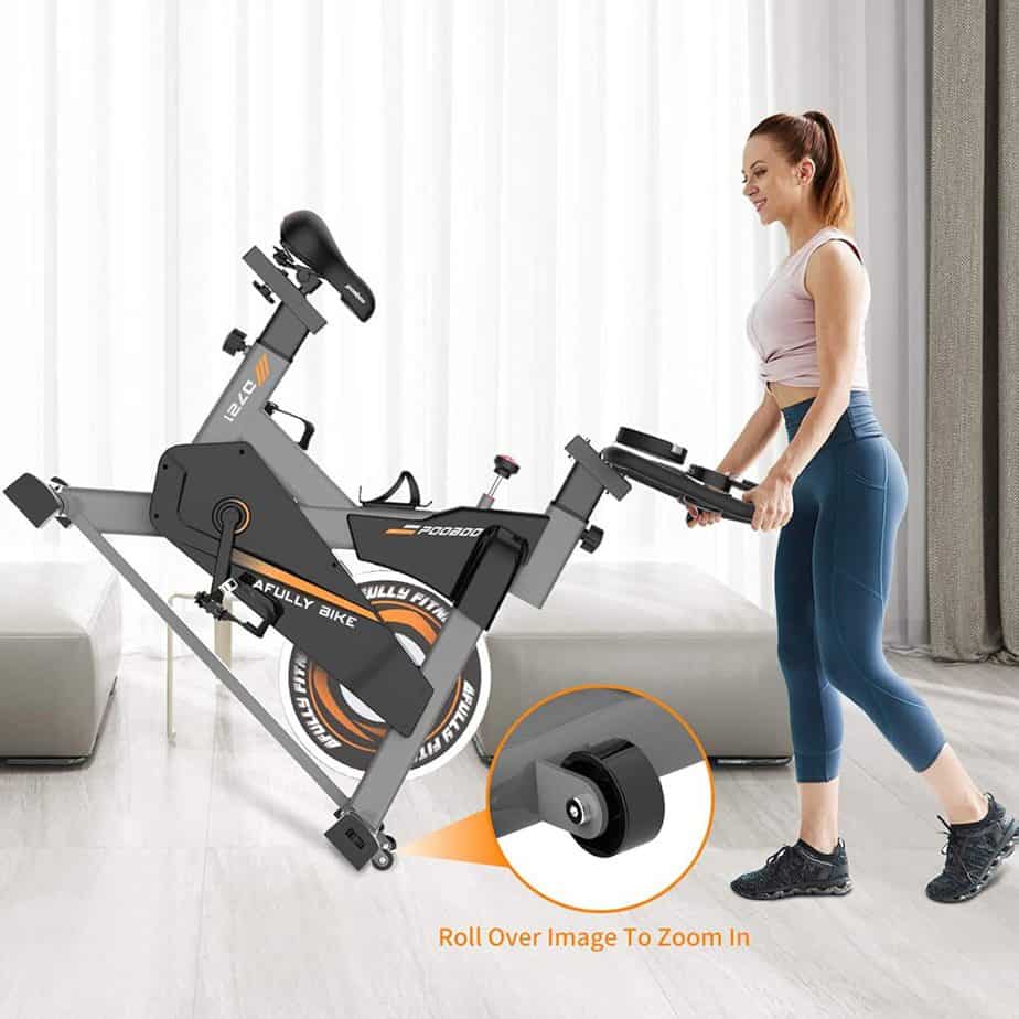 A user rolls the Pooboo S2 D721 Indoor Cycling Bike away for storage