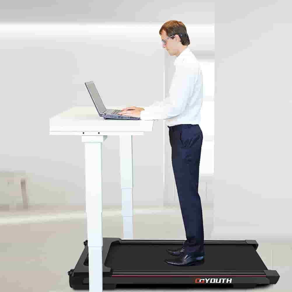 Man walks on the GOYOUTH 2-in-1 Under-Desk Treadmill while working on a desk
