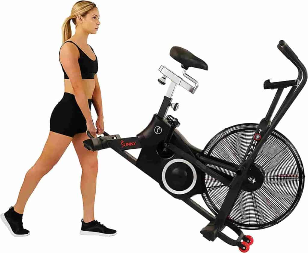 A lady moves the Sunny Health & Fitness SF-B2729 Air Bike to a storage area