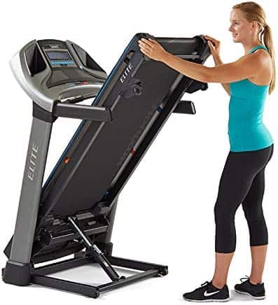 The folded HORIZON Elite T5 Treadmill is being moved by the user