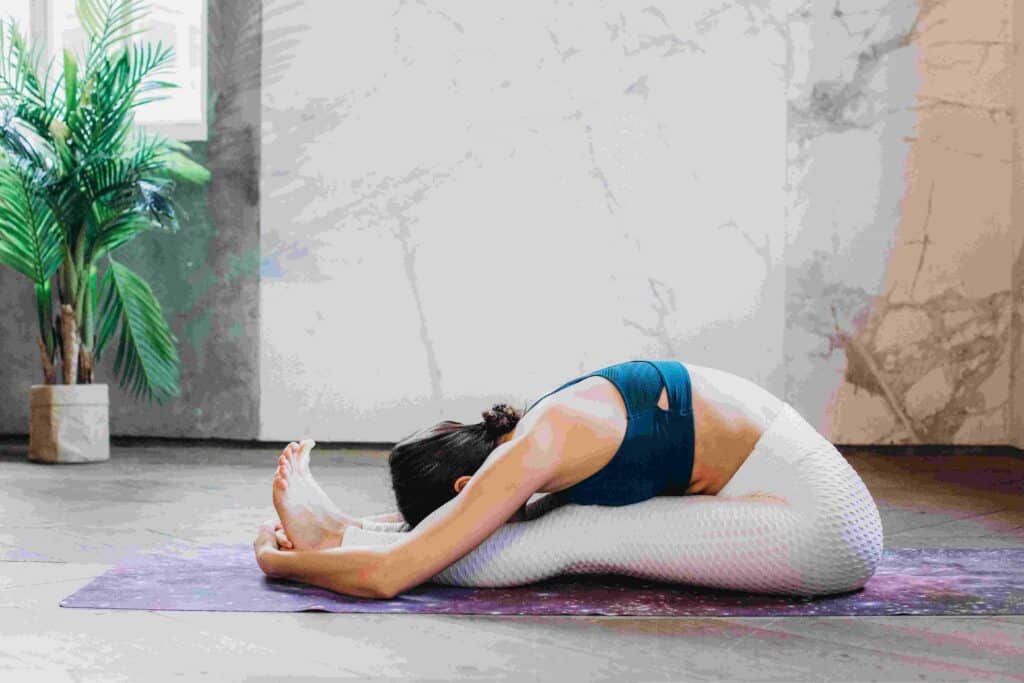 A lady practices seated forward bend yoga