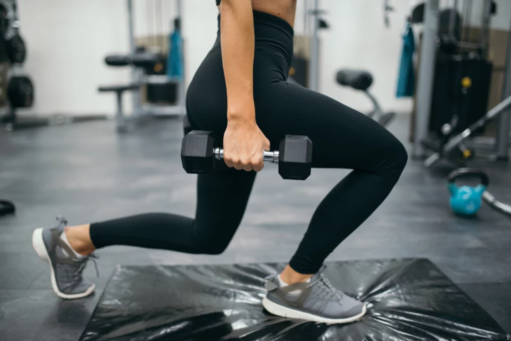 A woman does lunges with dumbbells