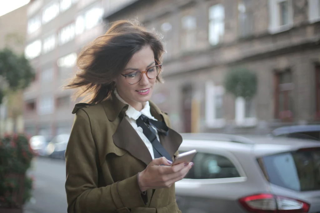 Woman looks at her smartphone while walking