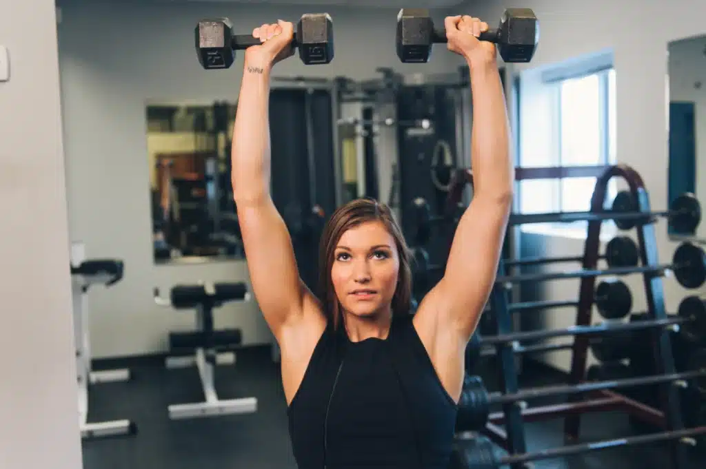 A woman performs the dumbbell press exercise